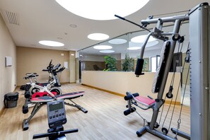 Ein Fitnessraum mit Cardiogeräten, Krafttrainingsgeräten und einem Spiegel.