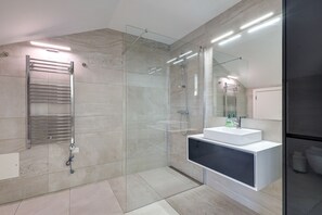 Et moderne badeværelse med en glasbrusekabine, en indbygget vask og en håndklædestang.