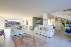 Ein modernes Wohnzimmer mit zwei weißen Sofas, einem Couchtisch und einem großen Fenster.