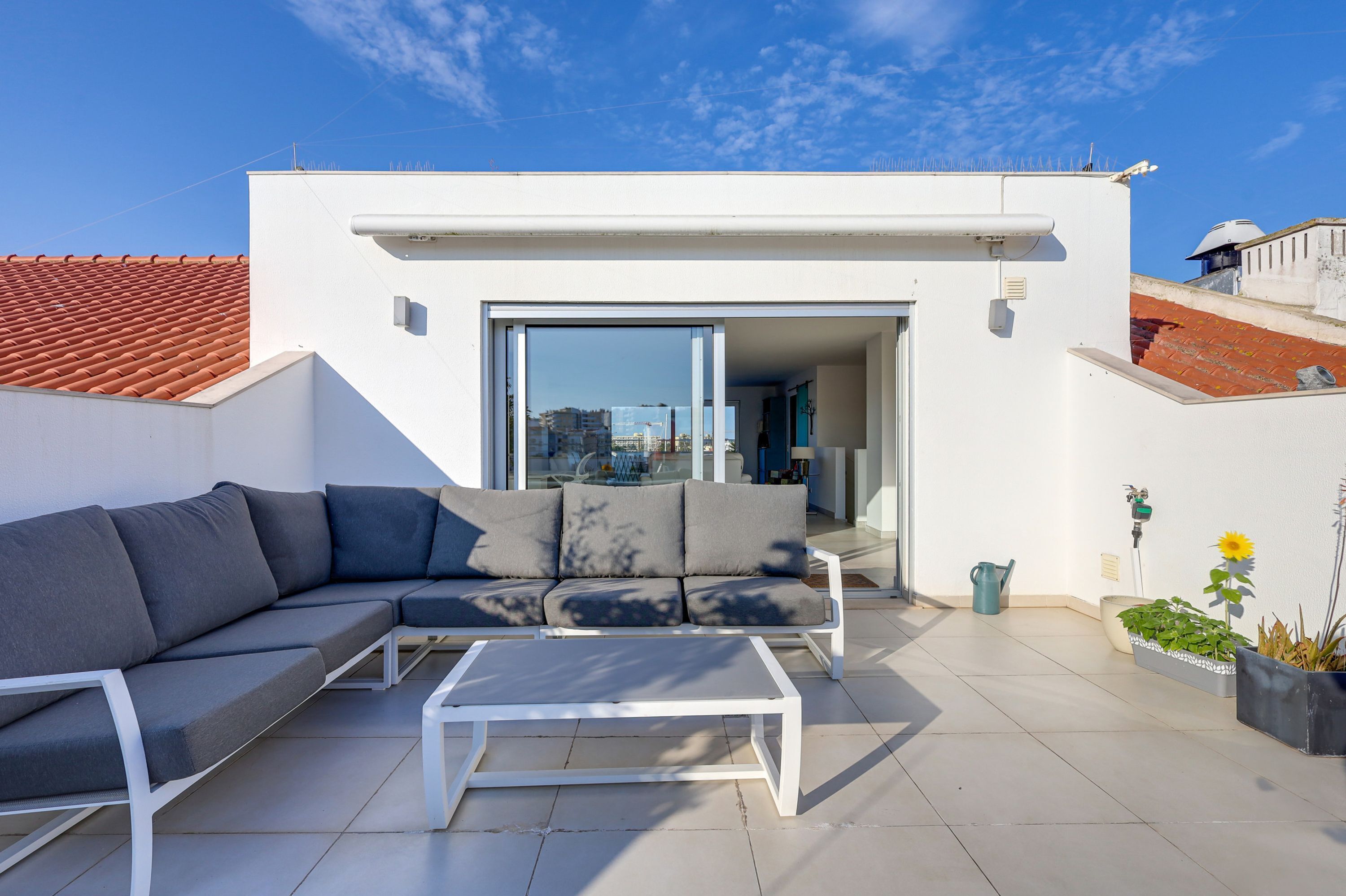 A modern outdoor patio with a sofa, coffee table, and potted plants.