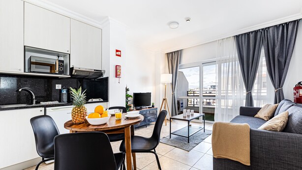 A modern living space with a kitchen, dining area, and a sofa with a view. - Encosta do Vau in Portim o (Portimão)