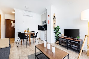 A modern living room with a dining area, a kitchen, and a TV on a wooden stand. - Encosta do Vau in Portim o (Portimão)