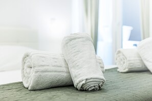 A neatly folded white towel on a green quilted bedspread in a hotel room. - Ncora Apartment Central Location Ne (Silves)