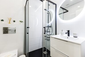 A modern bathroom with a glass-enclosed shower, a white sink with a black faucet, and a mirror with a circular frame. - Ncora Apartment Central Location Ne (Silves)