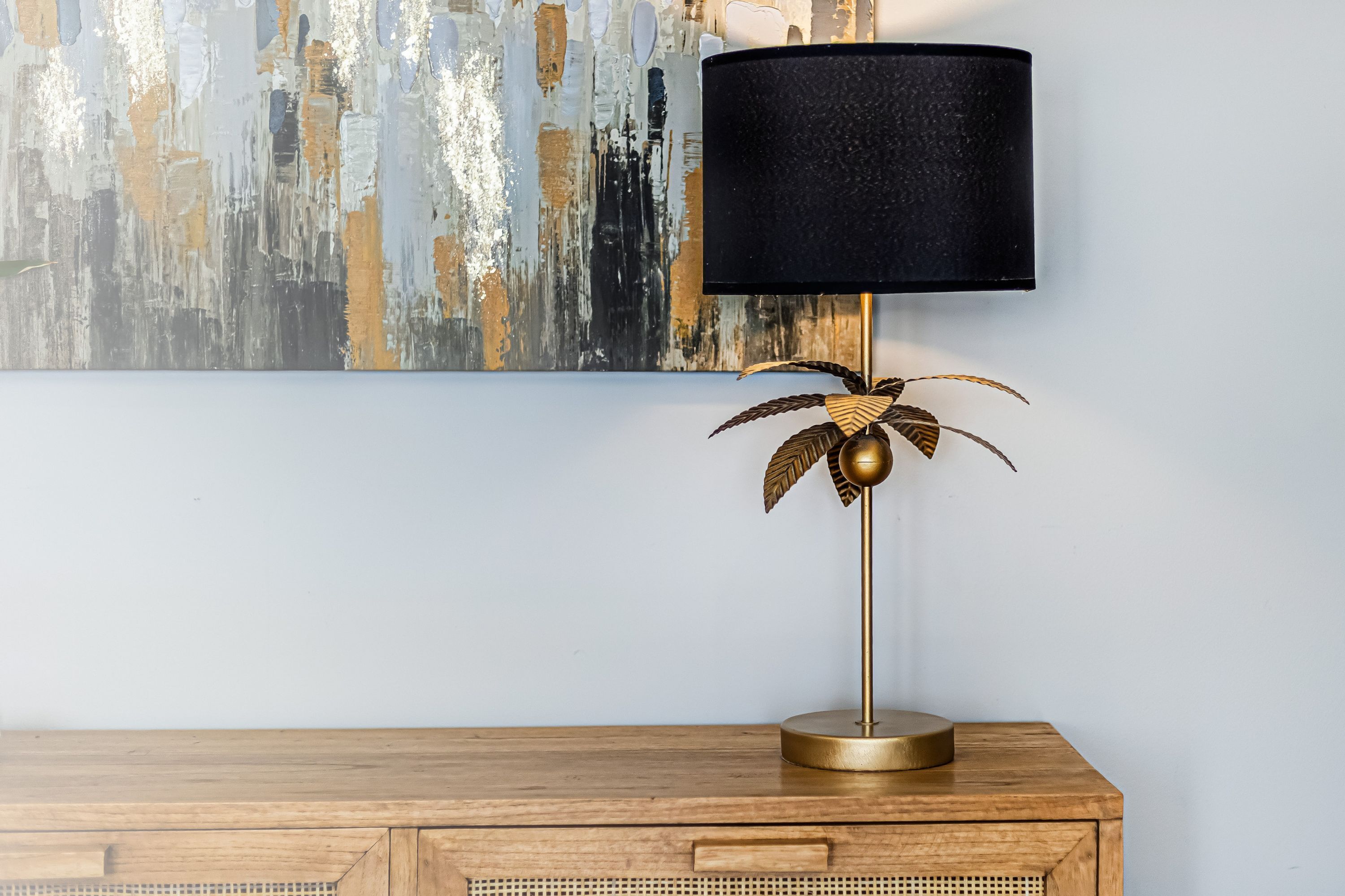 A lamp with a black shade and a gold base on a wooden surface.