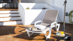 A sun lounger with a cushion, a book, a glass of orange juice, and a bowl of blueberries on a wooden stool. - Casa Oliva Ref gio Rural Contempor neo (Beja)