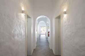 A hallway with white walls, a tiled floor, and two doors with light fixtures. - Casa Oliva Ref gio Rural Contempor neo (Beja)