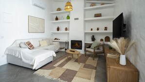 A modern living room with a fireplace, white walls, and a television. - Casa Oliva Ref gio Rural Contempor neo (Beja)