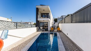 A modern building with a pool, outdoor seating, and a clear sky. - Casa Colina II Pool BBQ Family Retreat (Silves)