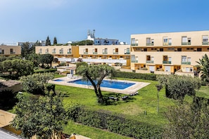A residential building with a swimming pool, green lawns, and a clear sky. - Casa Sol Vilamoura (Loulé)