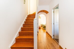 A wooden staircase leading to a room with a green couch and a lamp. - Casa Sol Vilamoura (Loulé)