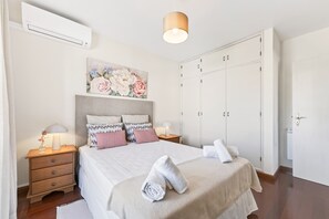 Ein Schlafzimmer mit Bett, Nachttischen, einer Lampe, einem Bild und einem Kleiderschrank.