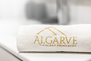 Ein weißes Handtuch mit eingesticktem Text 'ALGARVE GOLDEN PROPERTIES'.