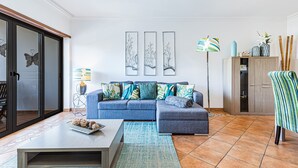 A living room with a blue sofa, a coffee table, a patterned rug, and wall art. - Sea La Vie On the Beach City Center Marina (Lagos)