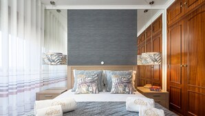 A hotel room with a bed, wooden wardrobe, and a nightstand with a lamp. - Sea La Vie On the Beach City Center Marina (Lagos)