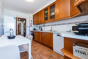 Eine Küche mit Holzausstattung, einer weißen Arbeitsplatte, einem Geschirrspüler und einer Mikrowelle.