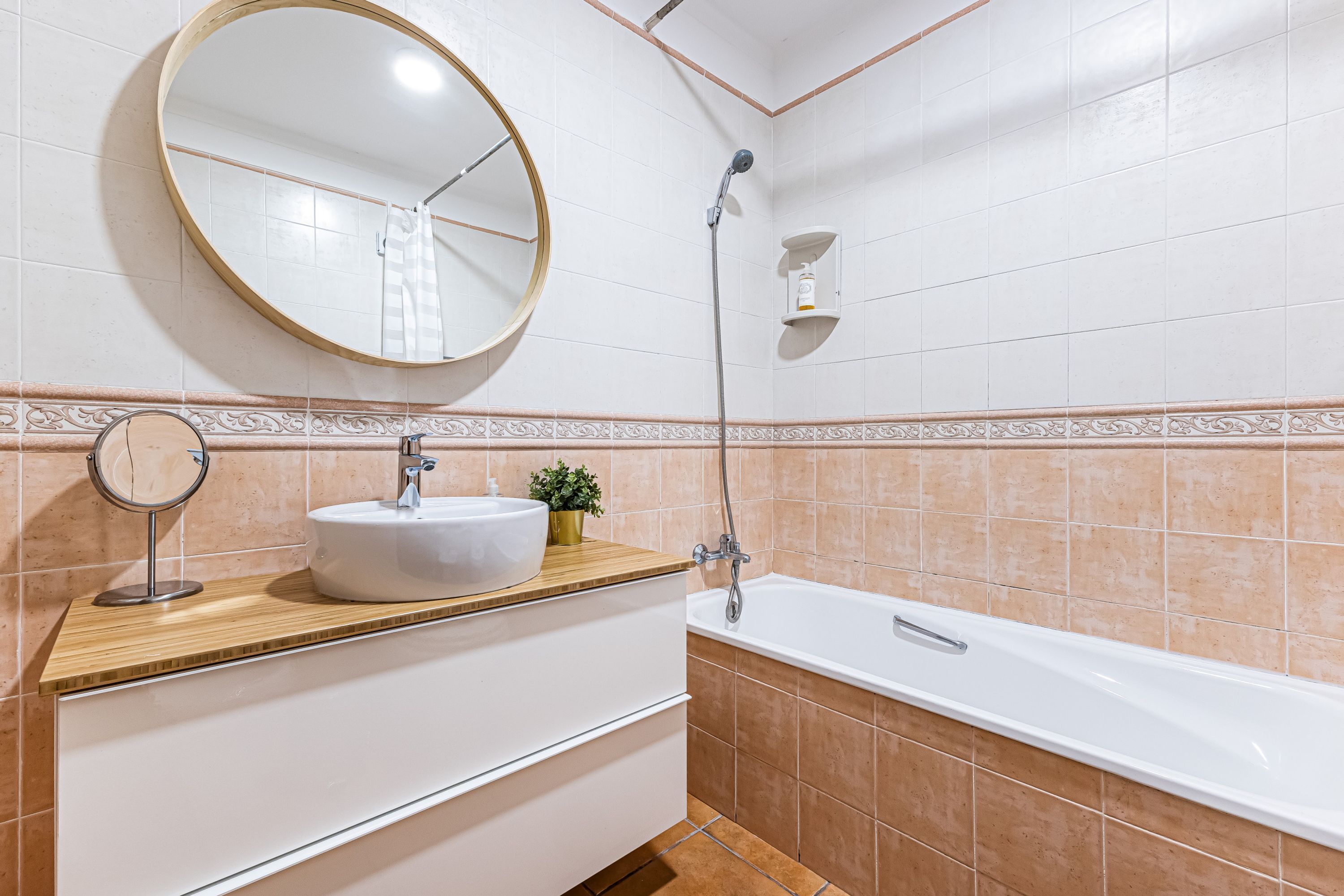 A bathroom with a round mirror, a sink, a shower, and a bathtub.
