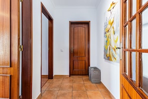Ein Flur mit Holztüren, gefliestem Boden und einem an der Wand hängenden Kunstwerk.