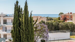 Ein Wohngebiet mit Gebäuden, einem Baum und Blick auf das Meer.