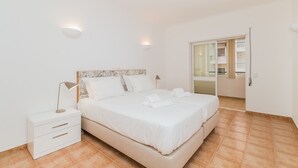 Ein Schlafzimmer mit Bett, Nachttischen, einer Lampe und einem durchgehenden Türspalt sichtbaren Badezimmer.