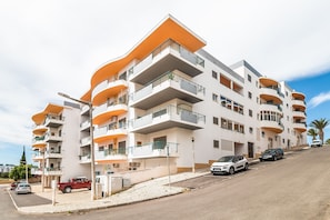 A multi-story residential building with balconies, a parking area, and a clear sky. - Casa da Gal Near Meia Praia Perfect Place w S (Lagos)