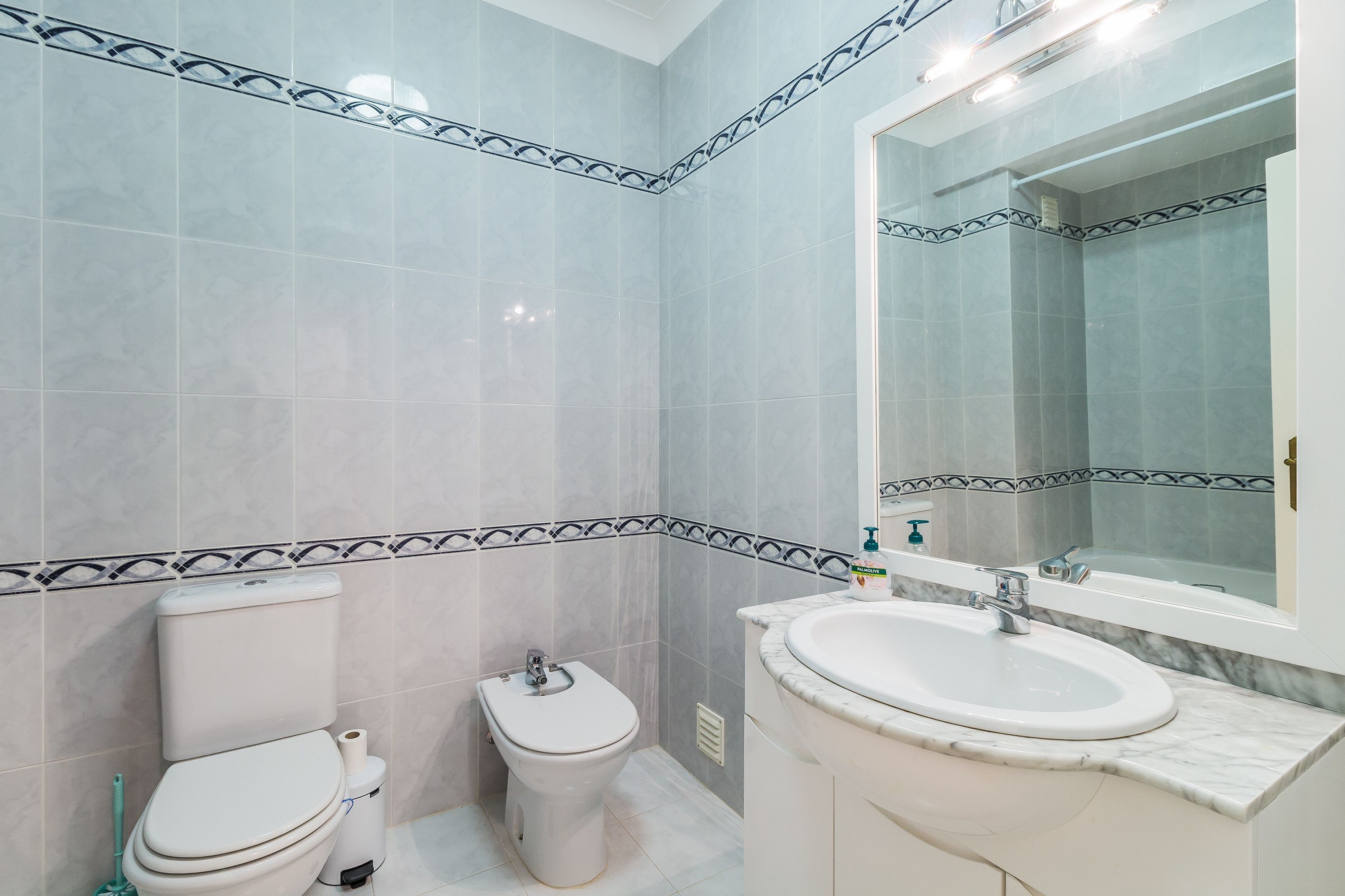 Une salle de bain avec des toilettes, un bidet et un lavabo, le tout de couleur blanche.