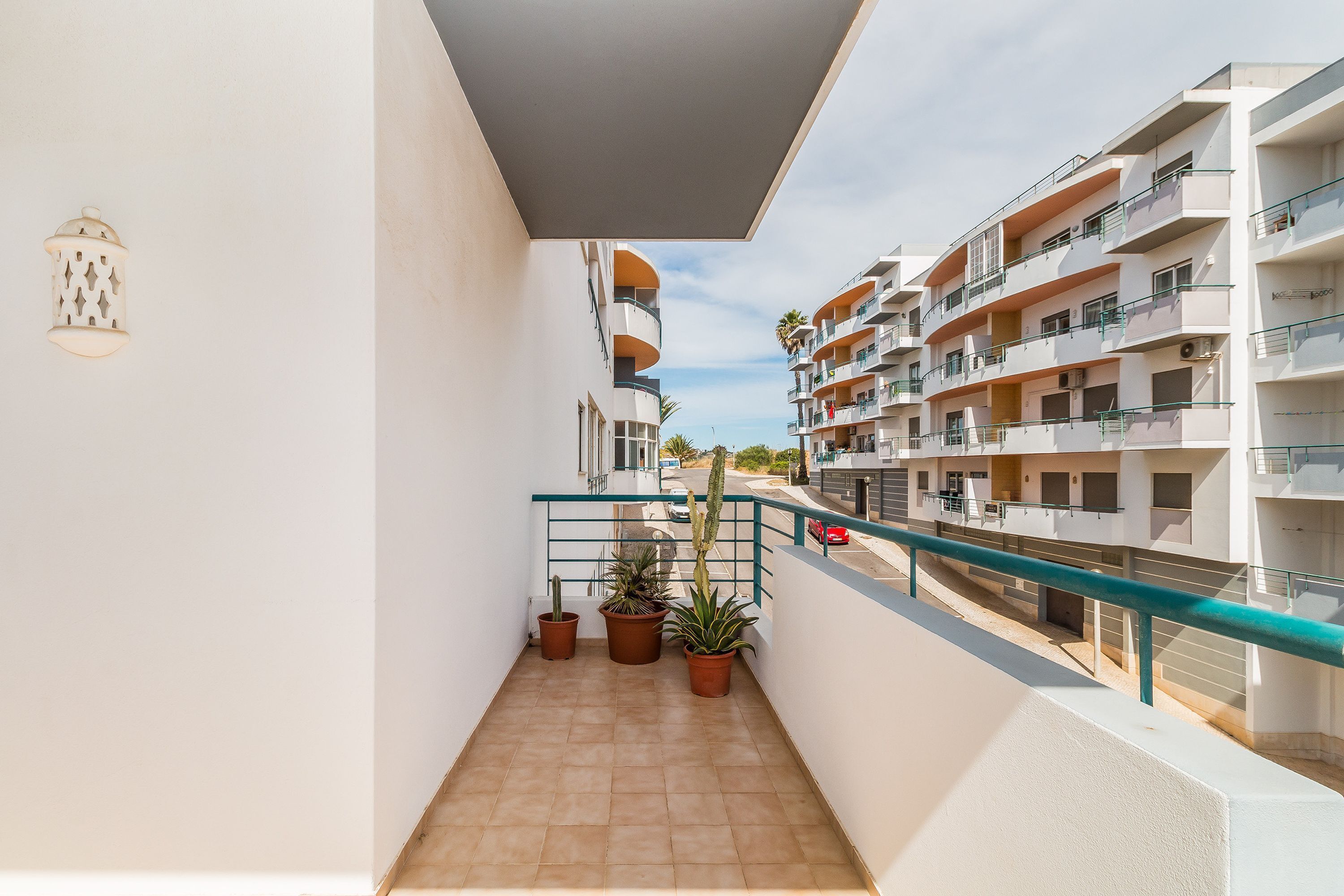 A balcony with potted plants, a railing, and a view of adjacent buildings.
