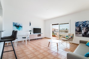 A modern living room with a TV, white furniture, a balcony with a view, and artwork on the walls. - Casa da Gal Near Meia Praia Perfect Place w S (Lagos)