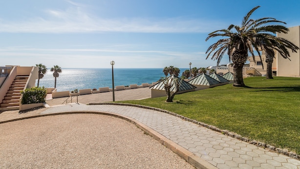 Un sendero pavimentado que lleva a un edificio con vista al mar.