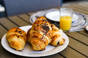A plate with croissants and a glass of orange juice on a wooden table. - Marina Village Pool Garage Prime Location AC (Lagos)