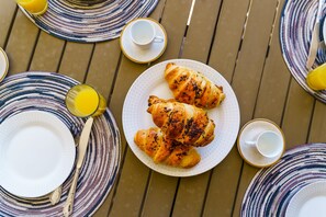 A table with croissants, plates, cutlery, and glasses, suggesting a breakfast setting. - Marina Village Pool Garage Prime Location AC (Lagos)