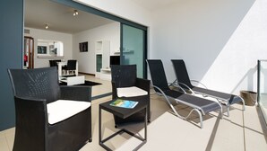 A balcony with four lounge chairs, a small table with a magazine, and a view of the interior. - Marina Village Pool Garage Prime Location AC (Lagos)