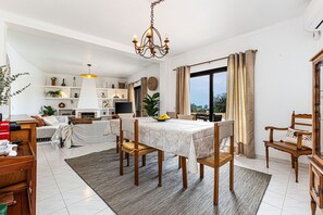 Ein Essbereich mit einem Tisch für vier Personen, einer Chandelier und Blick durch große Fenster.