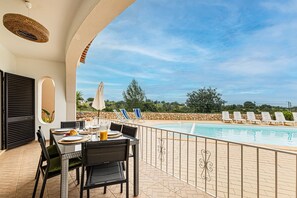 Ein Poolbereich mit Esstisch, Blick auf den Pool und Liegestühlen am Pool.