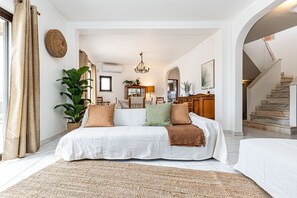 Ein großzügiges Wohnzimmer mit einer großen Couch, einem Couchtisch und einem Essbereich mit einem Chandelier.