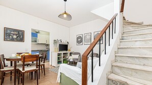 Ett kompakt bostadsutrymme med matplats, kök och en trappa.