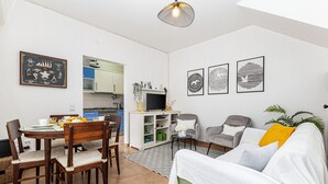 Ett kompakt bostadsutrymme med en matplats, ett litet kök och en soffa med en växt.