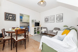 Ein modernes Wohnzimmer mit Essbereich, einer Couch und einem Fernseher.