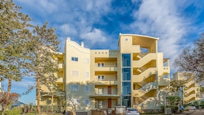 Edifício residencial com vários andares, varandas, escadaria central e área de estacionamento.