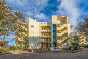 A multi-story residential building with balconies, a central staircase, and a parking area. - Meia Praia Beach Golf Perfect for Families Ent (Lagos)