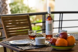 Uma mesa com uma garrafa, copos, uma tigela de frutas e uma cadeira.