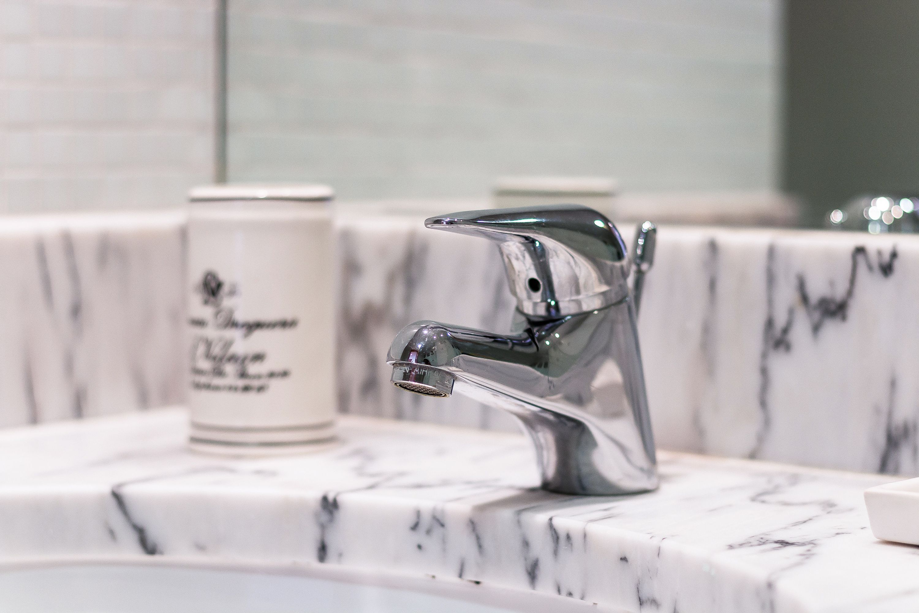 Une salle de bain dotée d’un lavabo moderne, d’un robinet chromé et d’un plan de toilette en marbre.