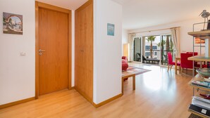 A room with a wooden door, a red chair, a table, and a view of the outside. - D Duarte On the Marina City Center and Beach (Lagos)