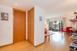 Ein Zimmer mit Holztür, einem roten Sessel, einem Tisch und Blick ins Freie.