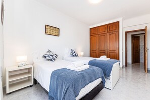 Ein Hotelzimmer mit zwei Betten, einem Holzschrank, einem Nachttisch mit Lampe und einem gerahmten Bild an der Wand.