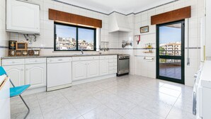 A modern kitchen with white cabinetry, a built-in oven, and a large window offering a city view. - Lagos Sea View Near the City Center (Lagos)