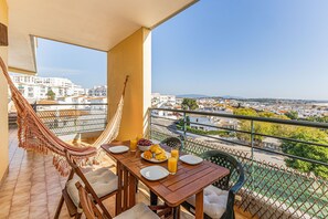 Ein Balkon mit Hängematte, Esstisch, Stühlen und Blick auf die Stadt.