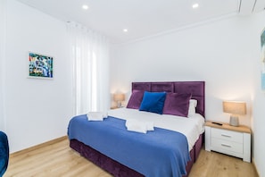 A modern bedroom with a bed, nightstands, and a painting on the wall. - Vista Bonita Dowtown Family (Lagos)