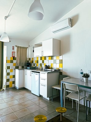 A compact kitchen with a dishwasher, a small dining area with a table and chairs, and a checkered backsplash. - Chilling Studio in Lagos (Lagos)