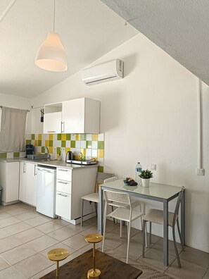 A compact kitchen with white cabinets, a small dining table, and a hanging light fixture. - Chilling Studio in Lagos (Lagos)